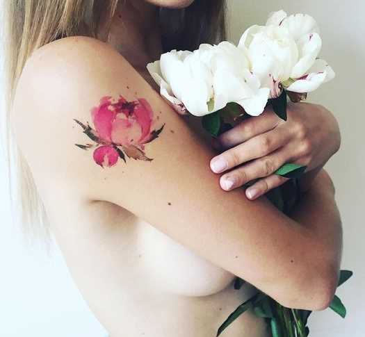 Foto de uma tatuagem de peônia no estilo aquarela no ombro da menina