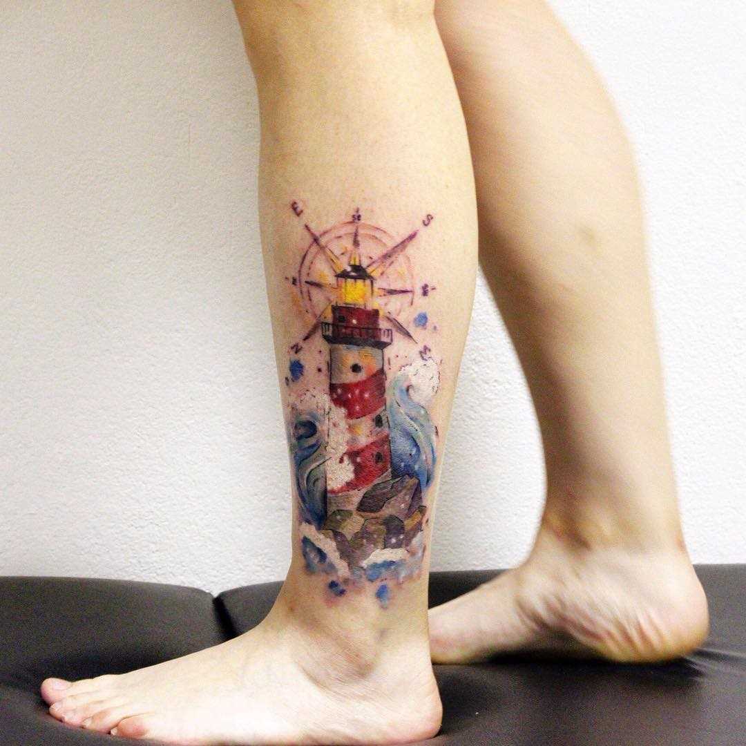 Foto de uma tatuagem de um farol em estilo newschool sobre a perna da menina