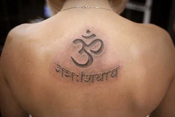 Foto de uma tatuagem do símbolo om no estilo indiano na parte de trás da menina