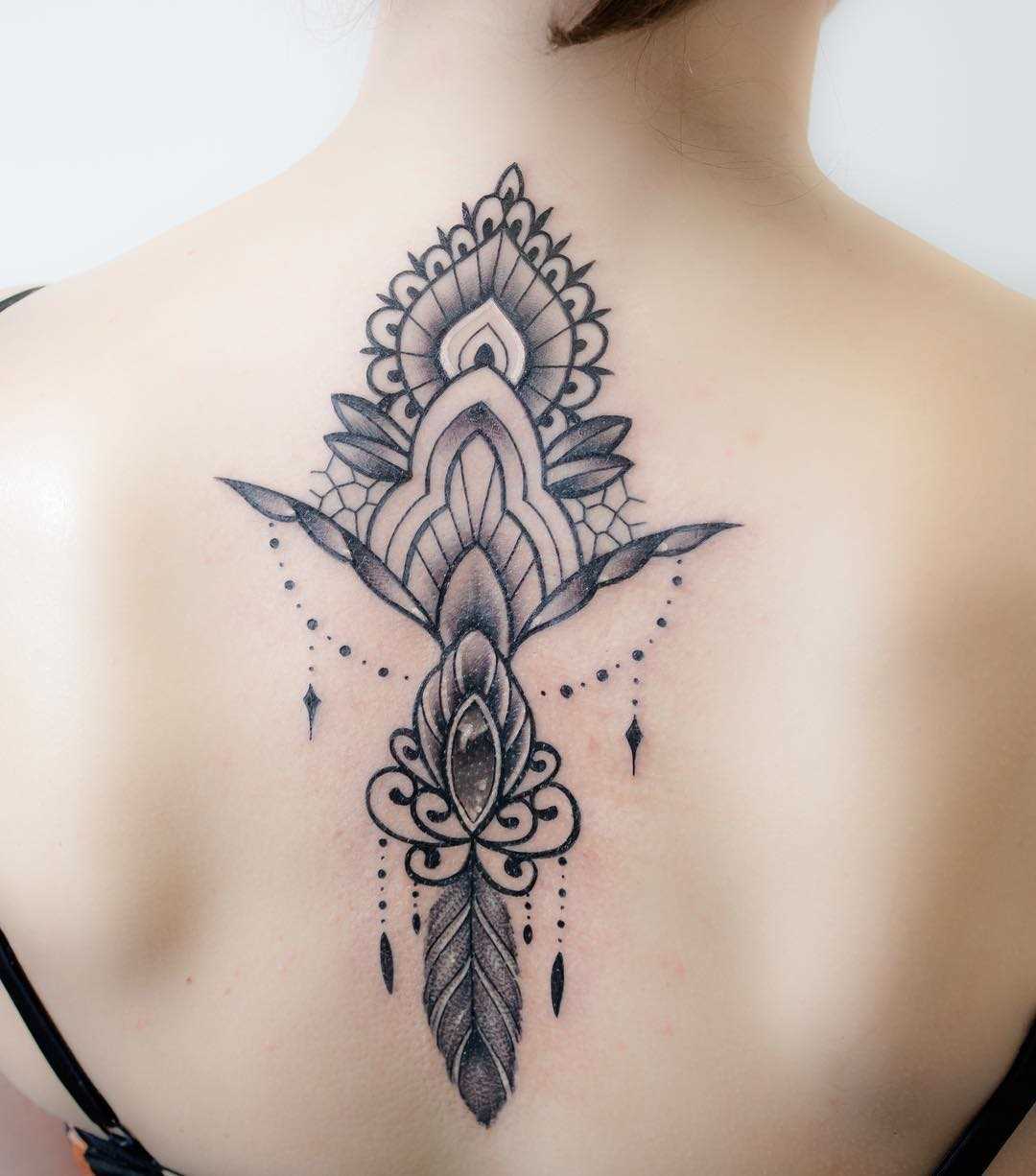Foto de uma tatuagem em estilo barroco na coluna da menina