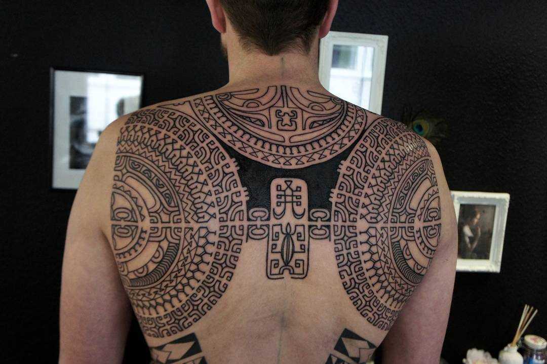 Foto de uma tatuagem em estilo polinésia nas costas do cara