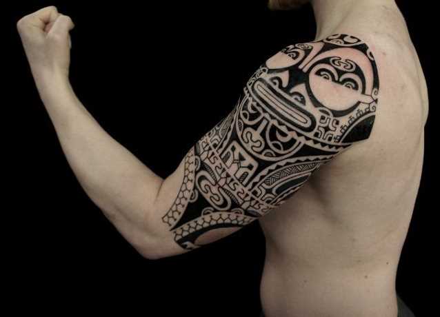 Foto de uma tatuagem em estilo polinésia no ombro do cara