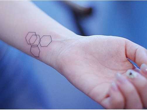 Foto pequena tatuagem no estilo de geometria no pulso da menina