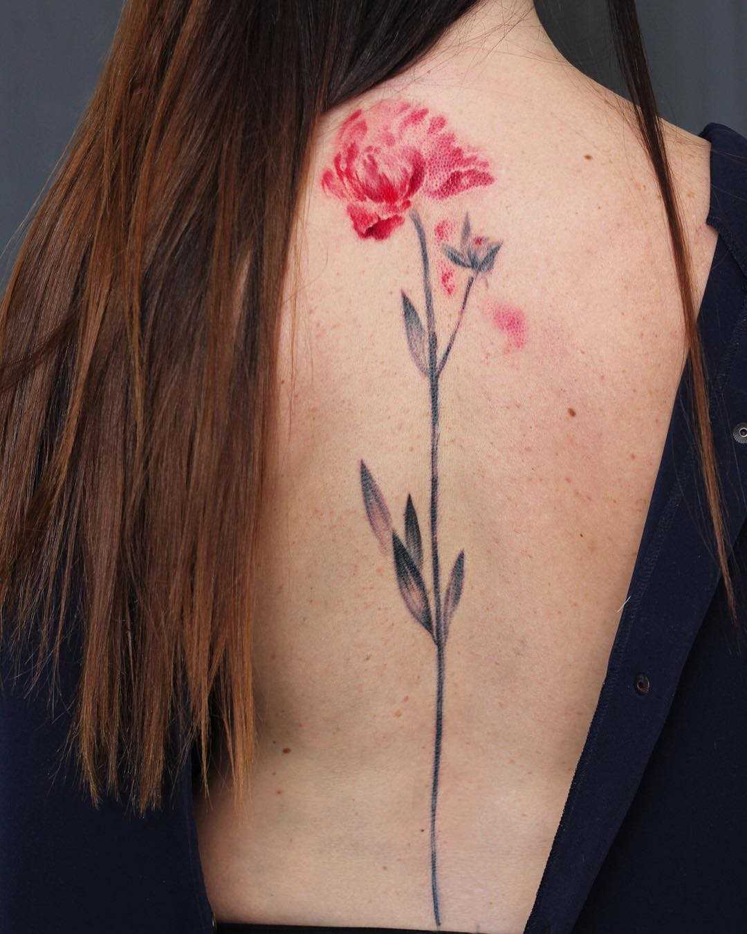 Fotos de tatuagem de flor no estilo aquarela sobre a espinha da menina