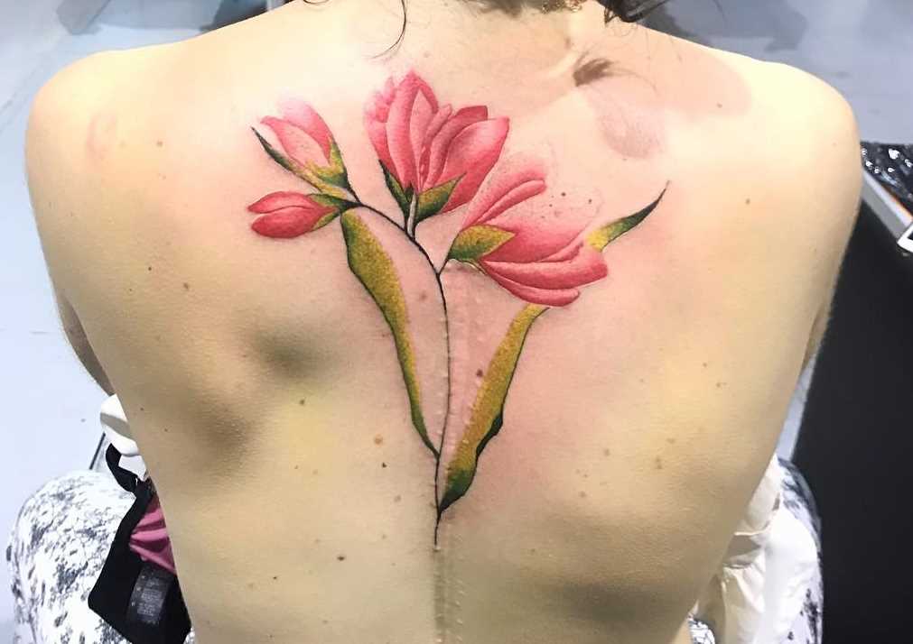 Fotos de tatuagem de flores no estilo aquarela na parte de trás da menina