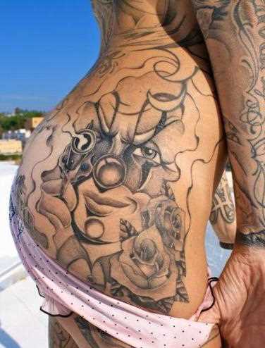 Latino-americano, a tatuagem chicano no quadril da menina - gangstersha, uma arma e uma rosa