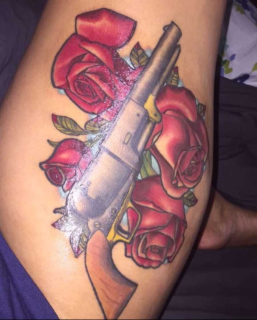 Legal tatuagem revólver com as rosas e a coxa da menina