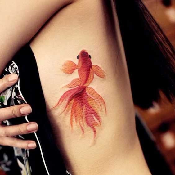 Linda tatuagem de peixe de ouro sobre as costelas menina