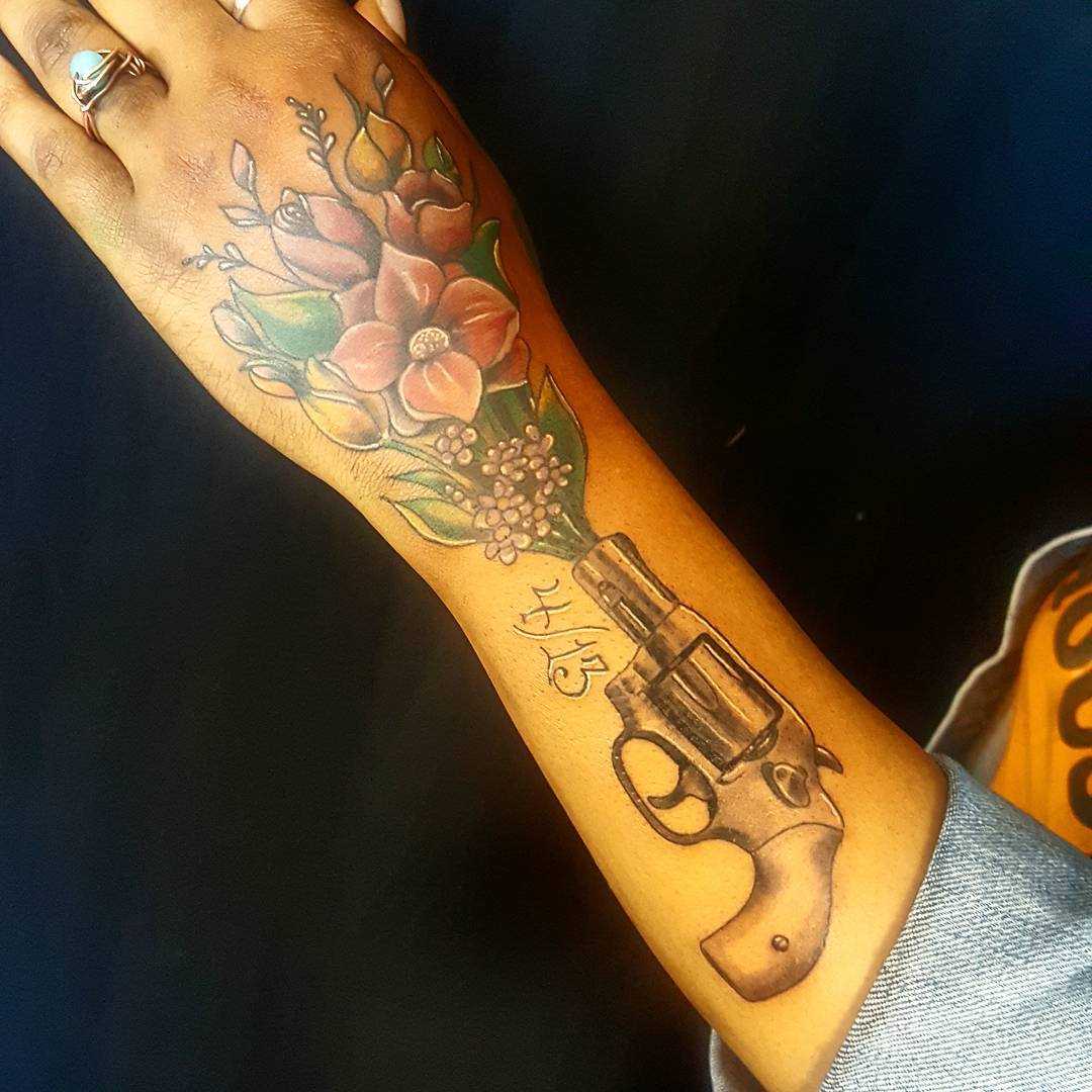 O desenho do revólver com flores no antebraço da menina