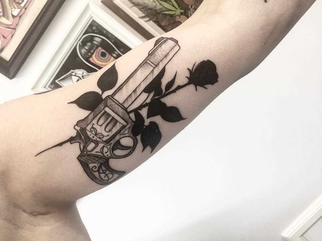 O desenho do revólver com uma rosa na mão da mulher