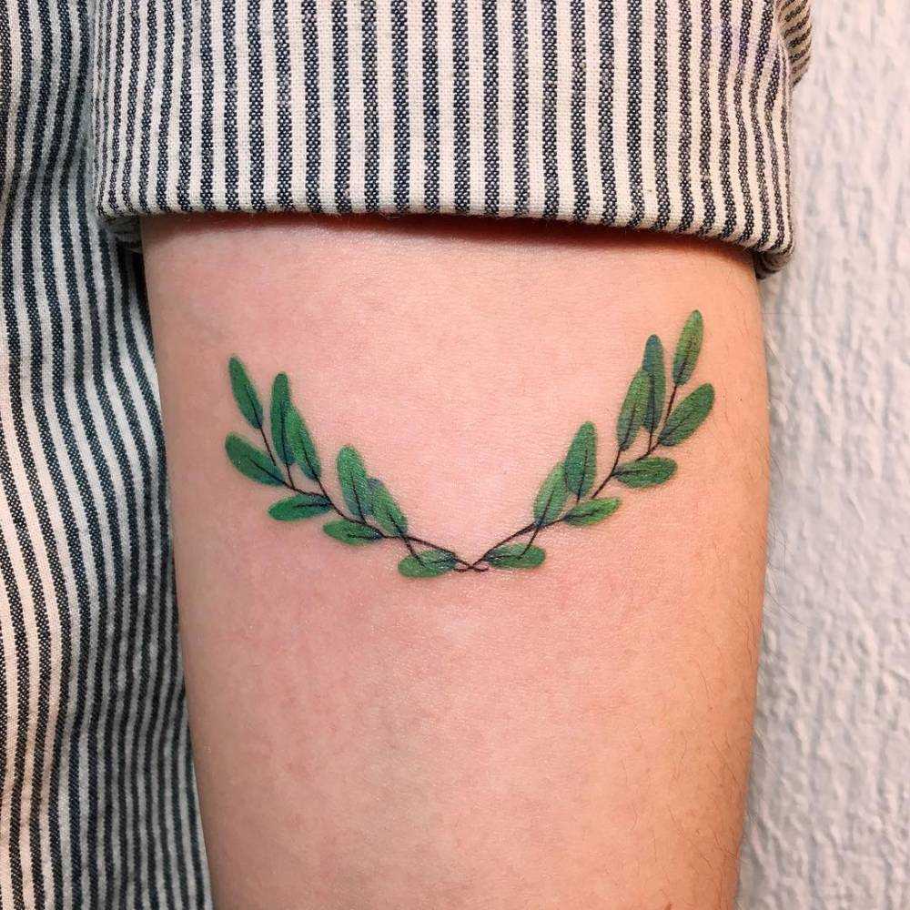O verde a tatuagem de coroa de louro na mão da menina