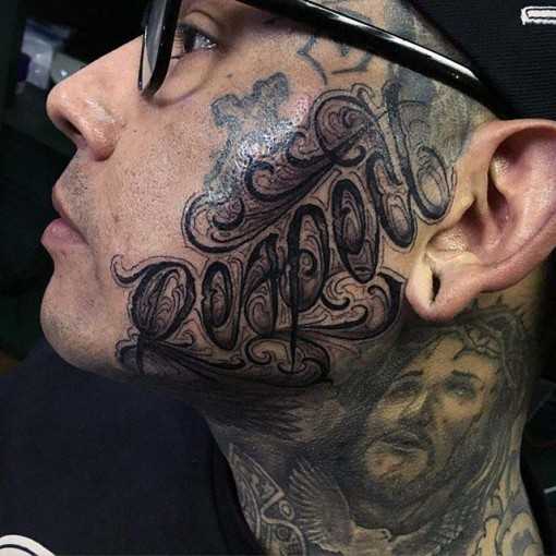 Tatuagem - a inscrição no estilo chicano no rosto do cara