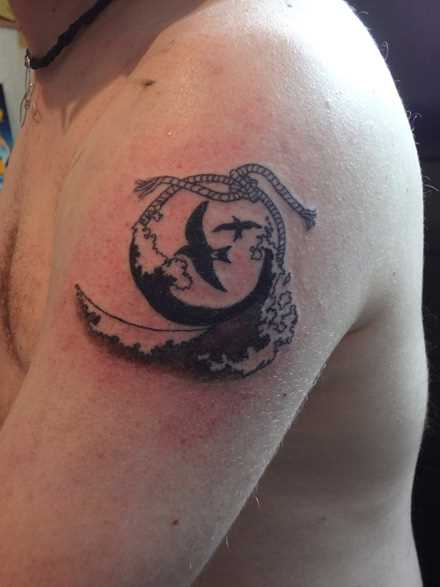 Tatuagem com uma gaivota no ombro do cara