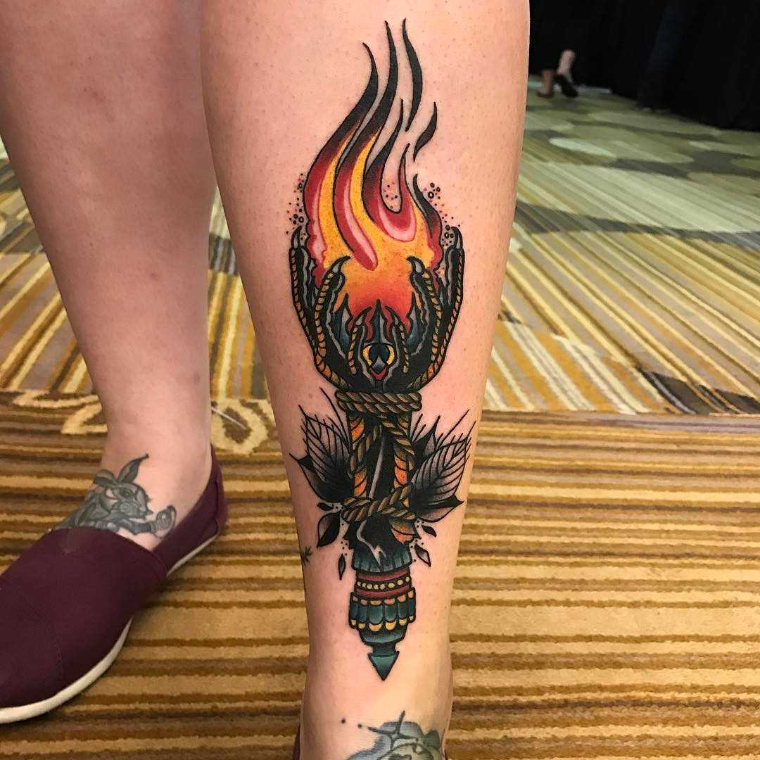 Tatuagem da tocha sobre a perna da mulher