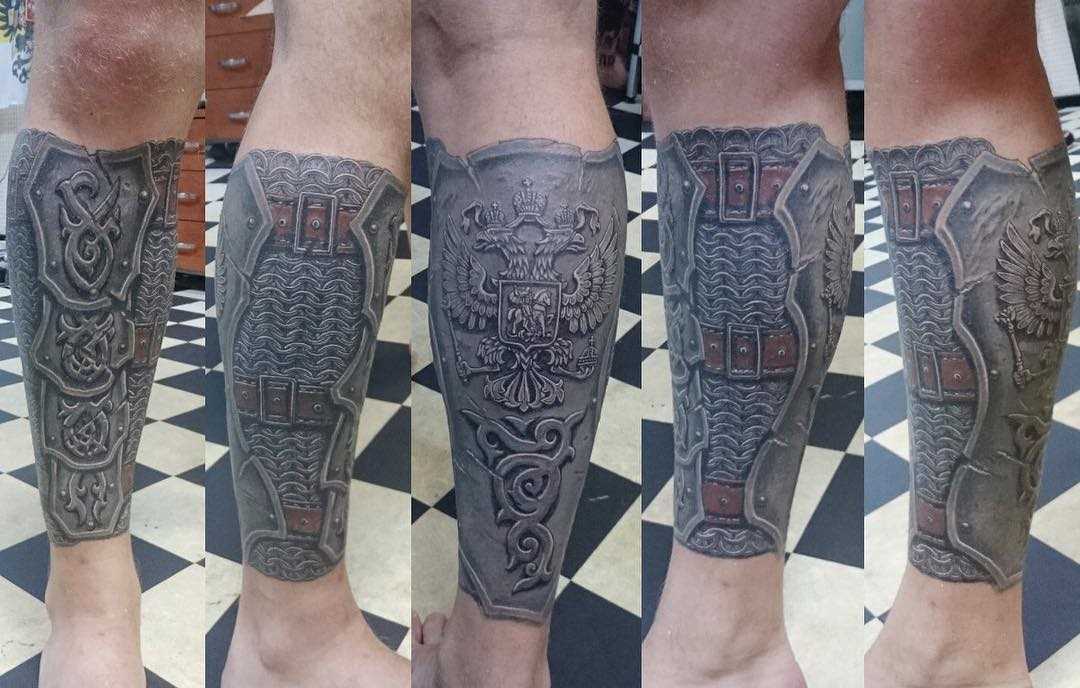 Tatuagem de armaduras com o brasão de armas sobre a perna de um cara