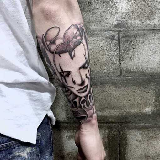 Tatuagem de chicano - a máscara do arlequim na mão de um cara