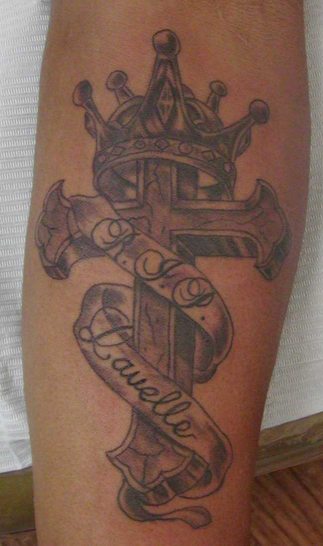 Tatuagem de coroa, a cruz e a fita com a inscrição no antebraço do homem, e a