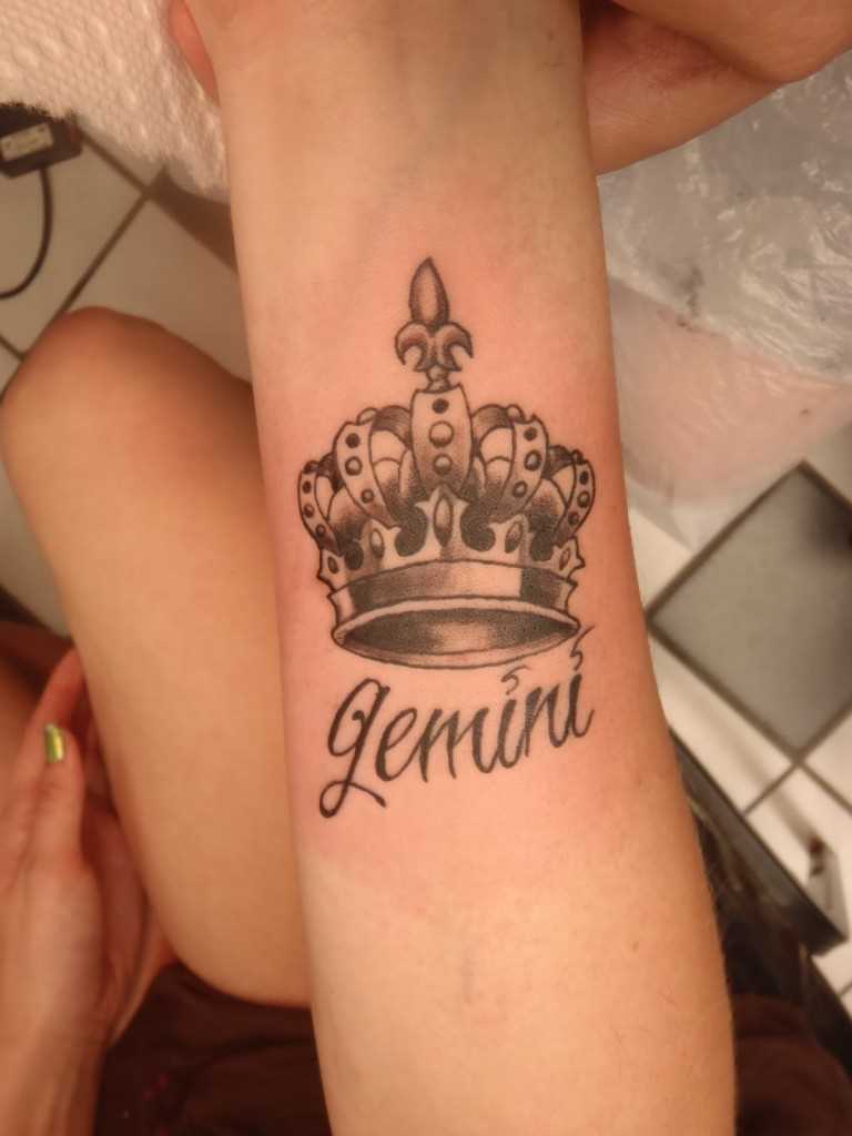 Tatuagem de coroa com a inscrição no pulso da menina