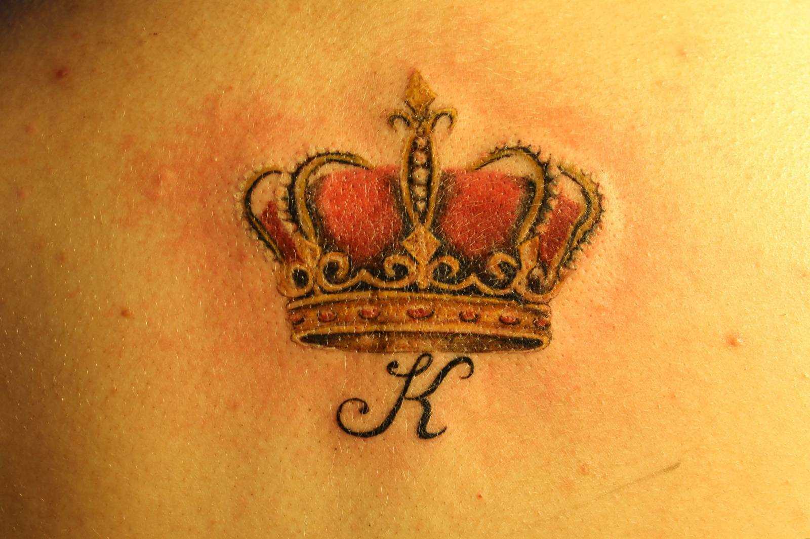 Tatuagem de coroa com a letra A na coluna vertebral do homem, e a