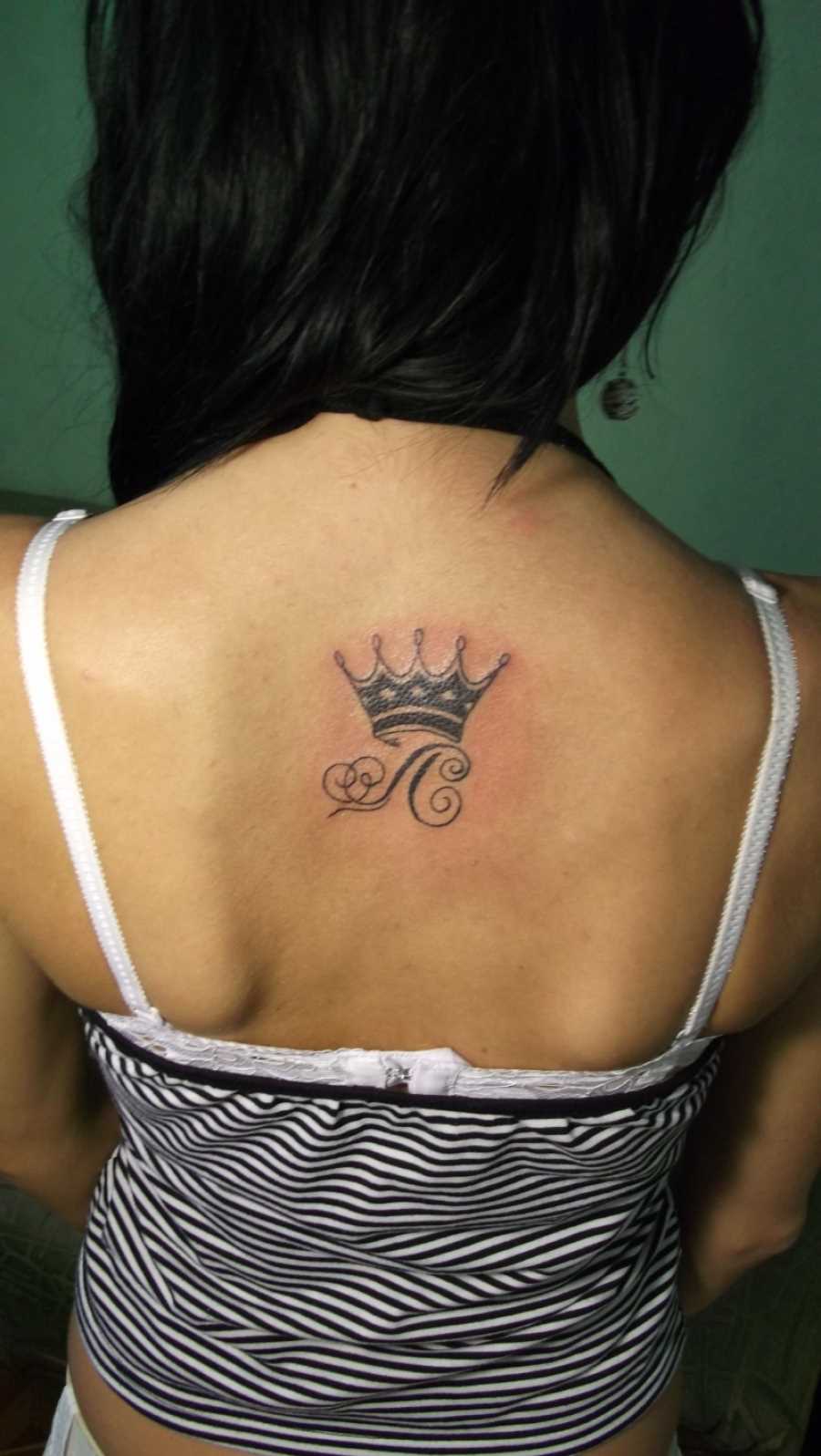Tatuagem de coroa com a letra L na espinha, as meninas