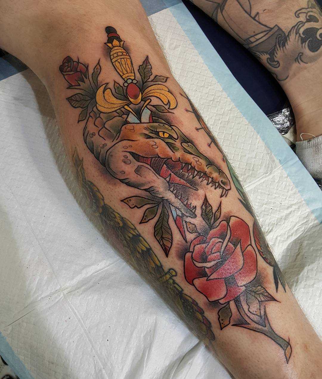 Tatuagem de crocodilo, com uma rosa na perna do cara