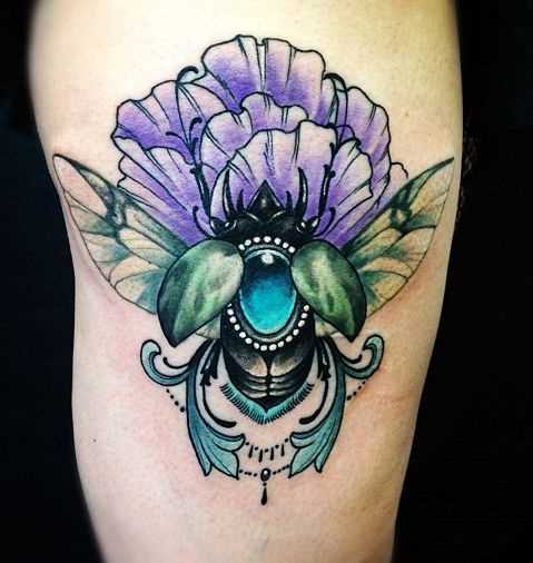 Tatuagem de escaravelho com uma flor no quadril da menina