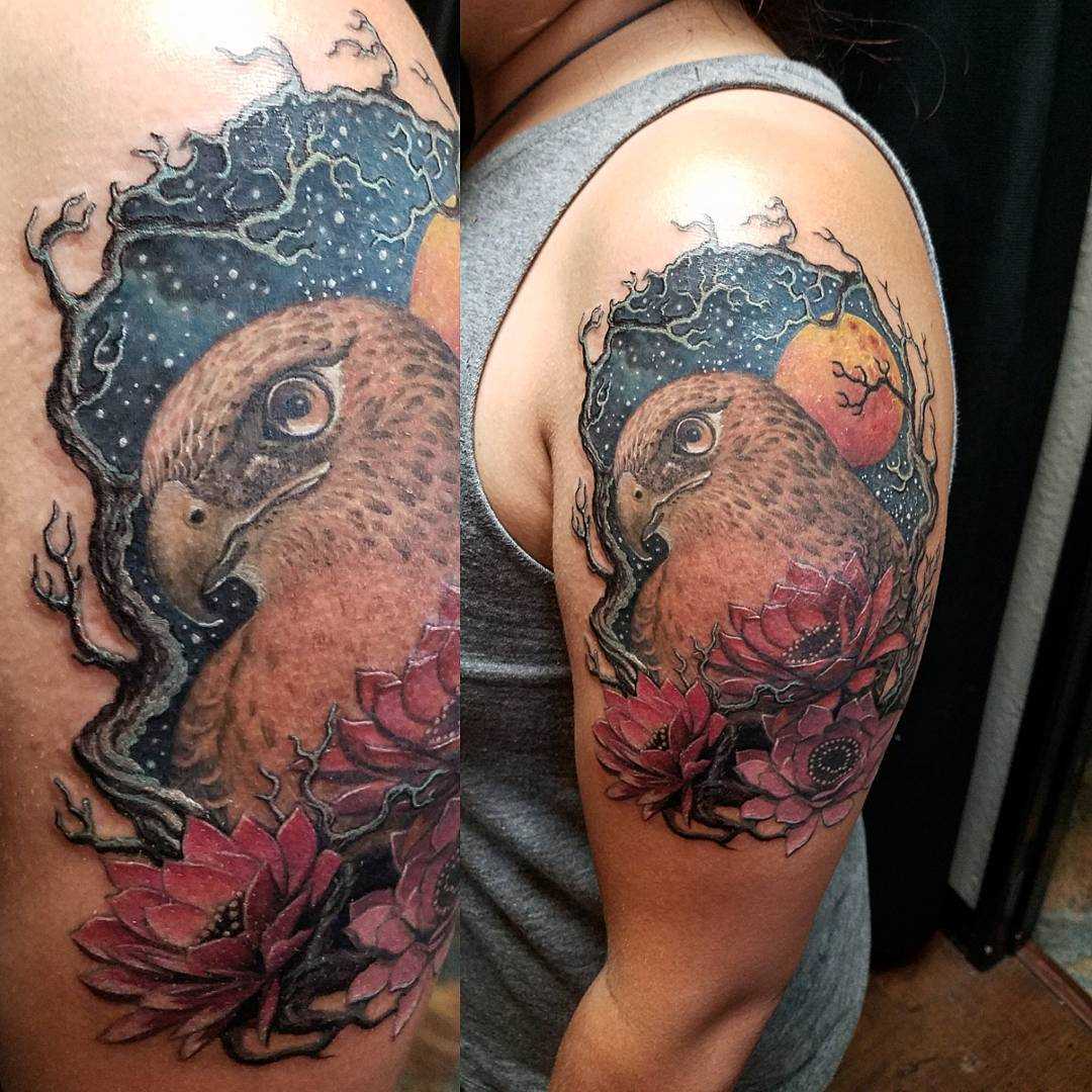 Tatuagem de falcão com flores no ombro da mulher