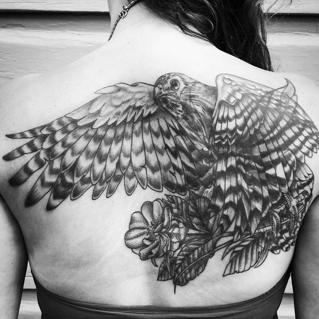 Tatuagem de falcão na parte de trás de uma mulher