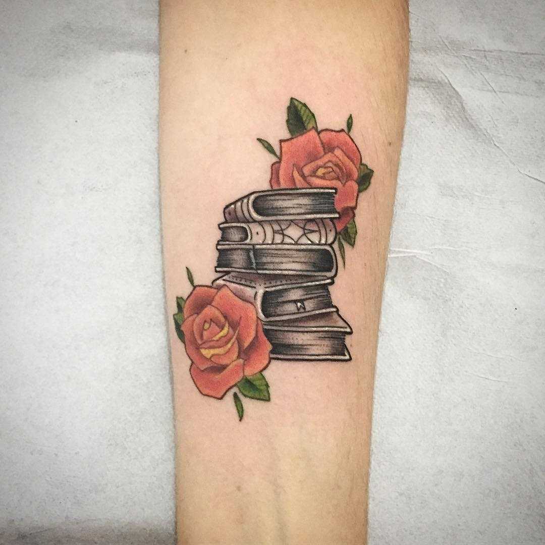 Tatuagem de livros com rosas no antebraço cara