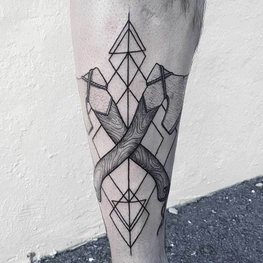 Tatuagem de machados sobre a perna de um cara