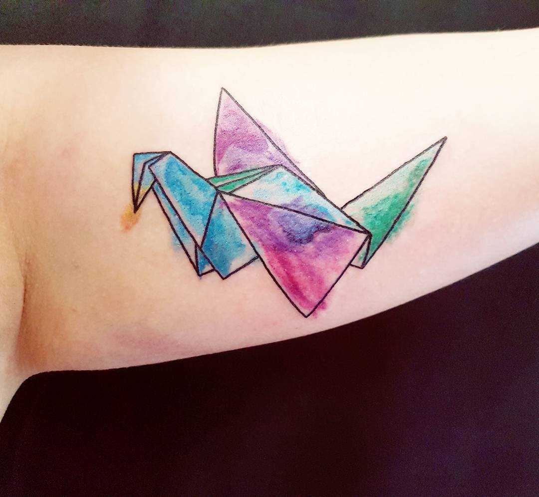 Tatuagem de origami-guindaste na mão da mulher