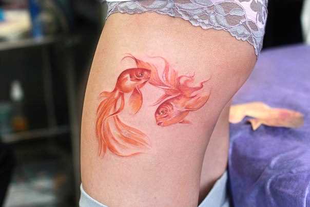 Tatuagem de peixes de ouro no quadril da menina