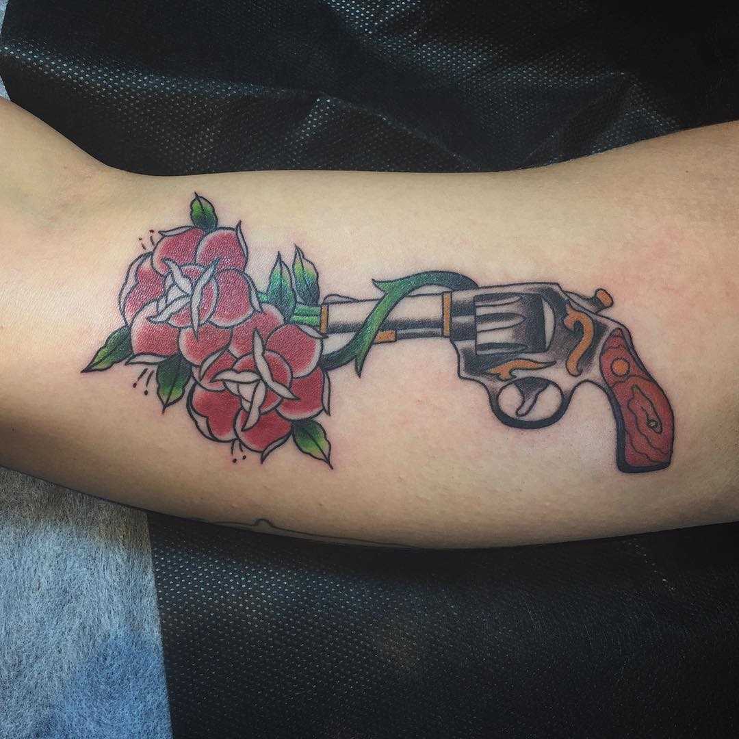Tatuagem de revólver com rosas na mão de homens