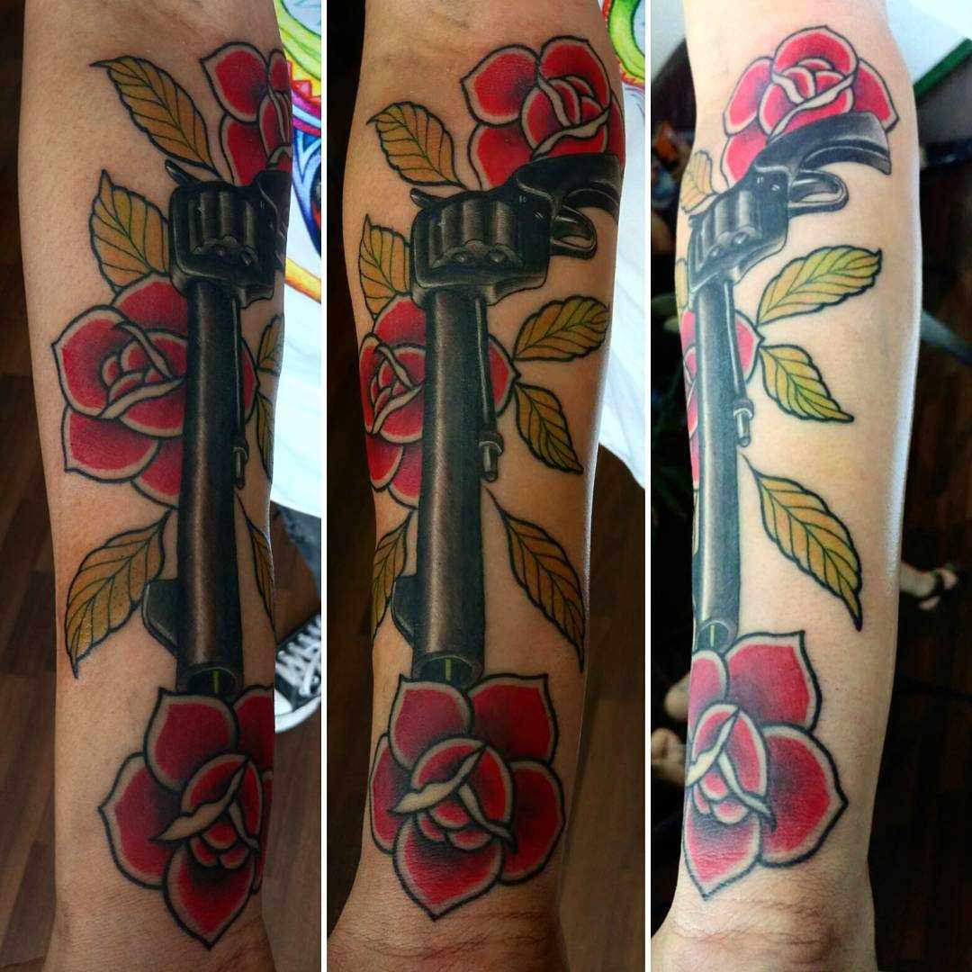 Tatuagem de revólver com rosas no antebraço homens