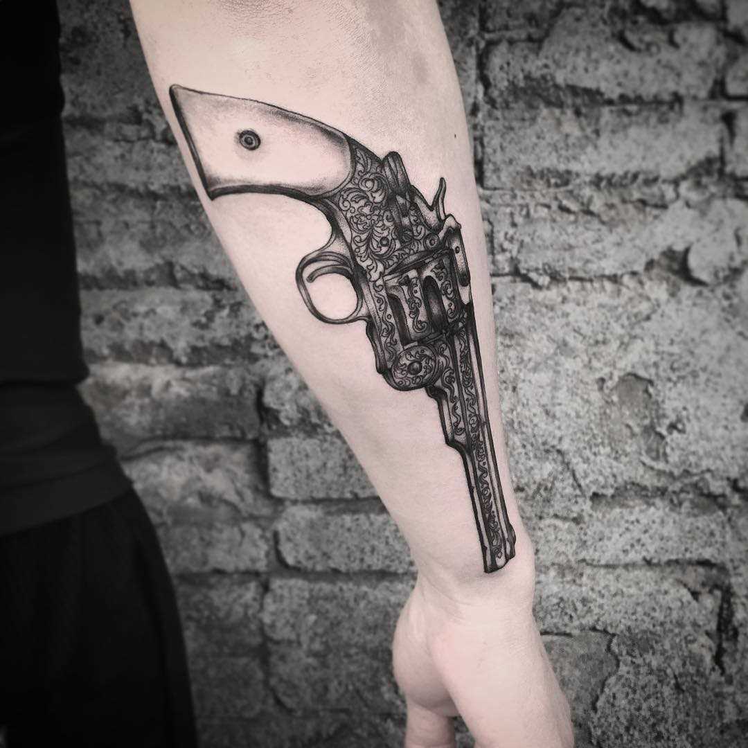 Tatuagem de revólver no antebraço cara