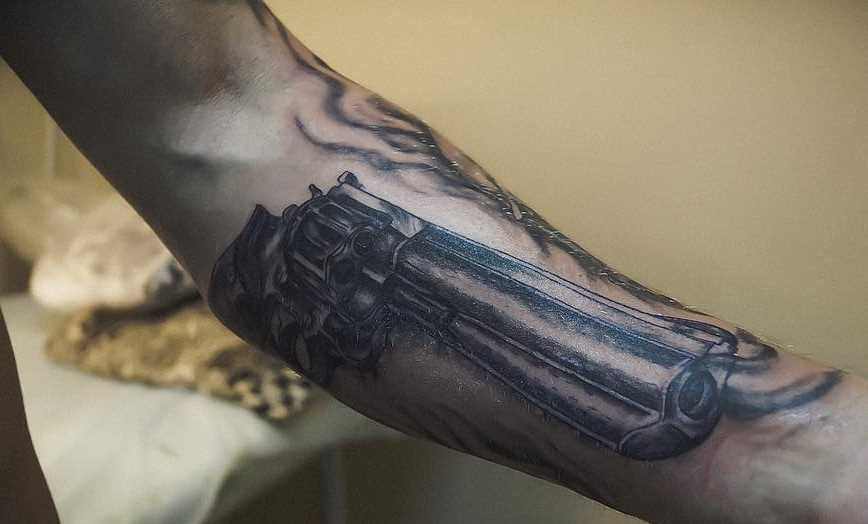 Tatuagem de revólver no antebraço homens