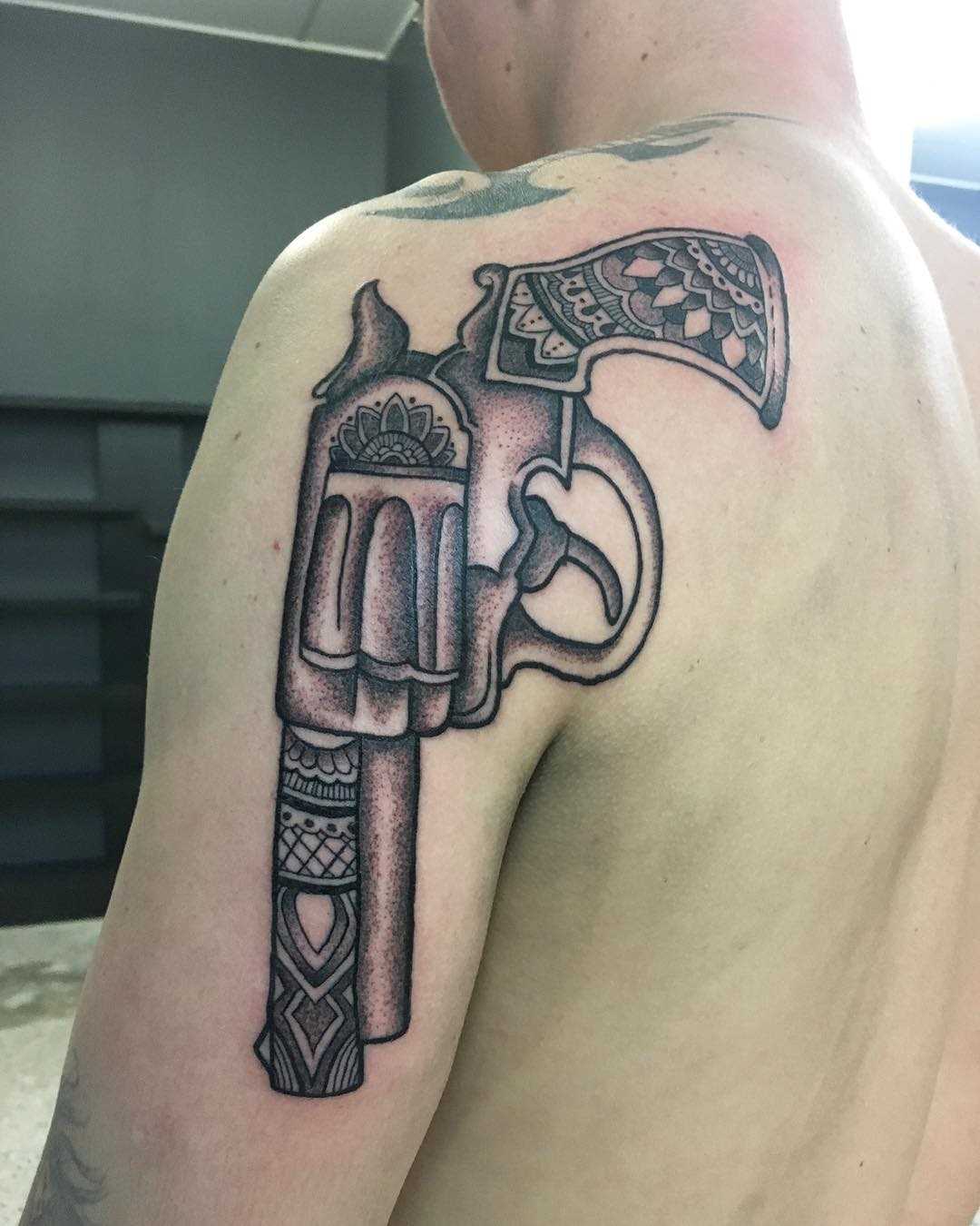 Tatuagem de revólver no ombro do cara