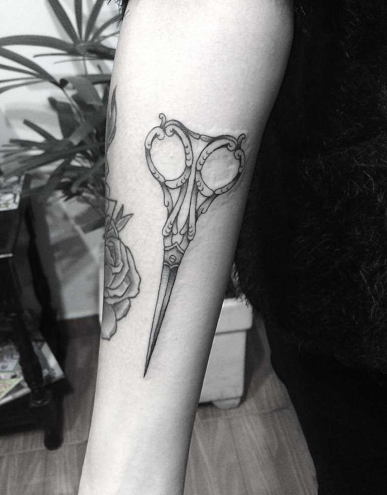 Tatuagem de tesoura no antebraço da menina
