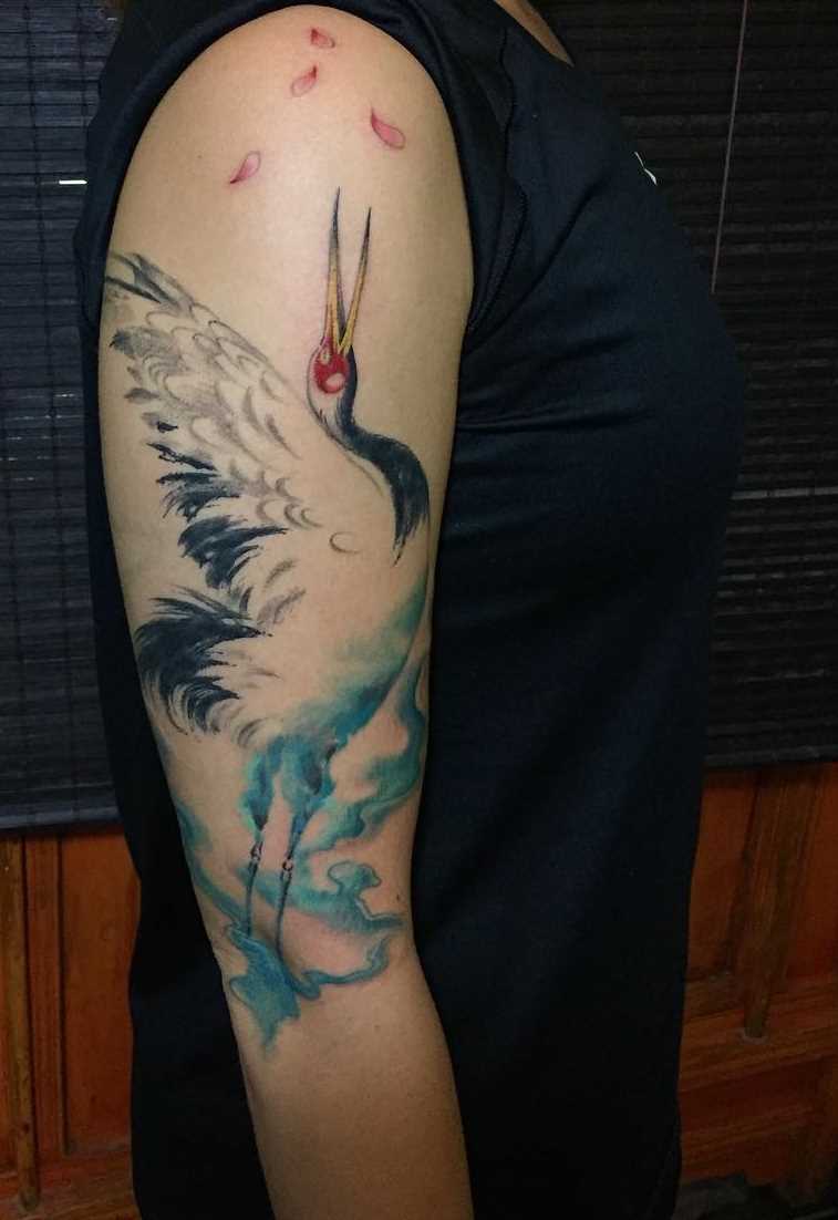 Tatuagem de um guindaste sobre o ombro de uma mulher