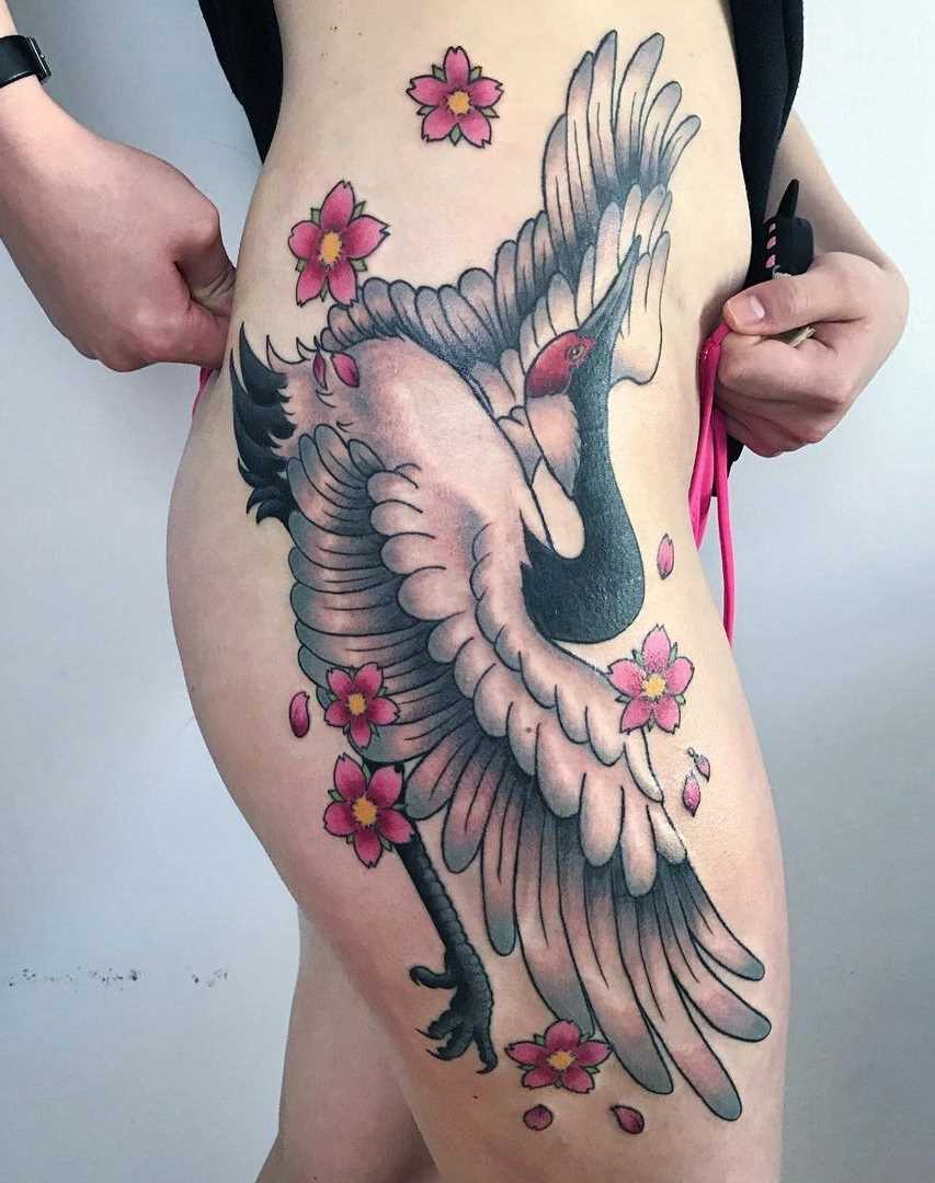 Tatuagem de um guindaste sobre o quadril da menina