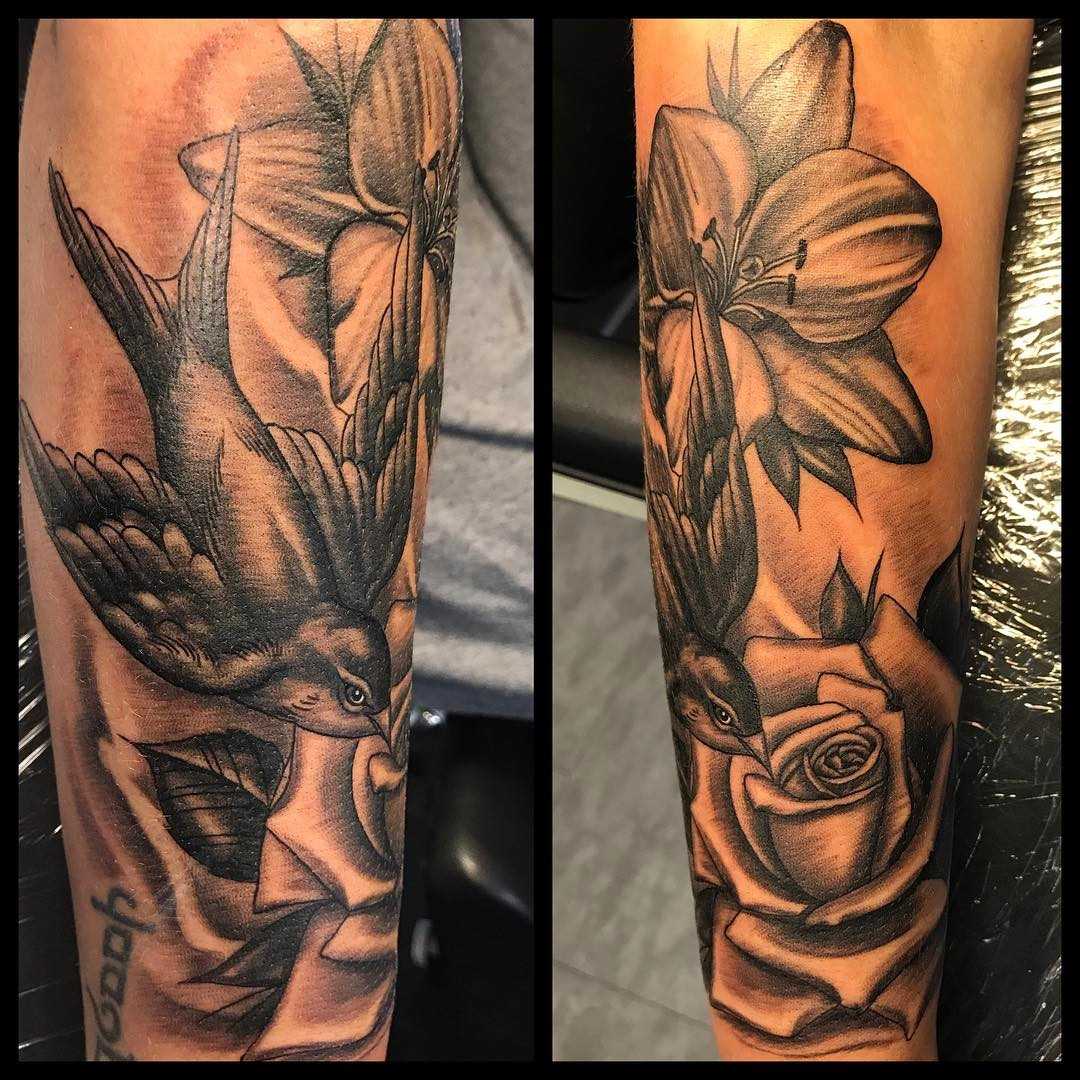 Tatuagem de um pardal com flores no antebraço cara