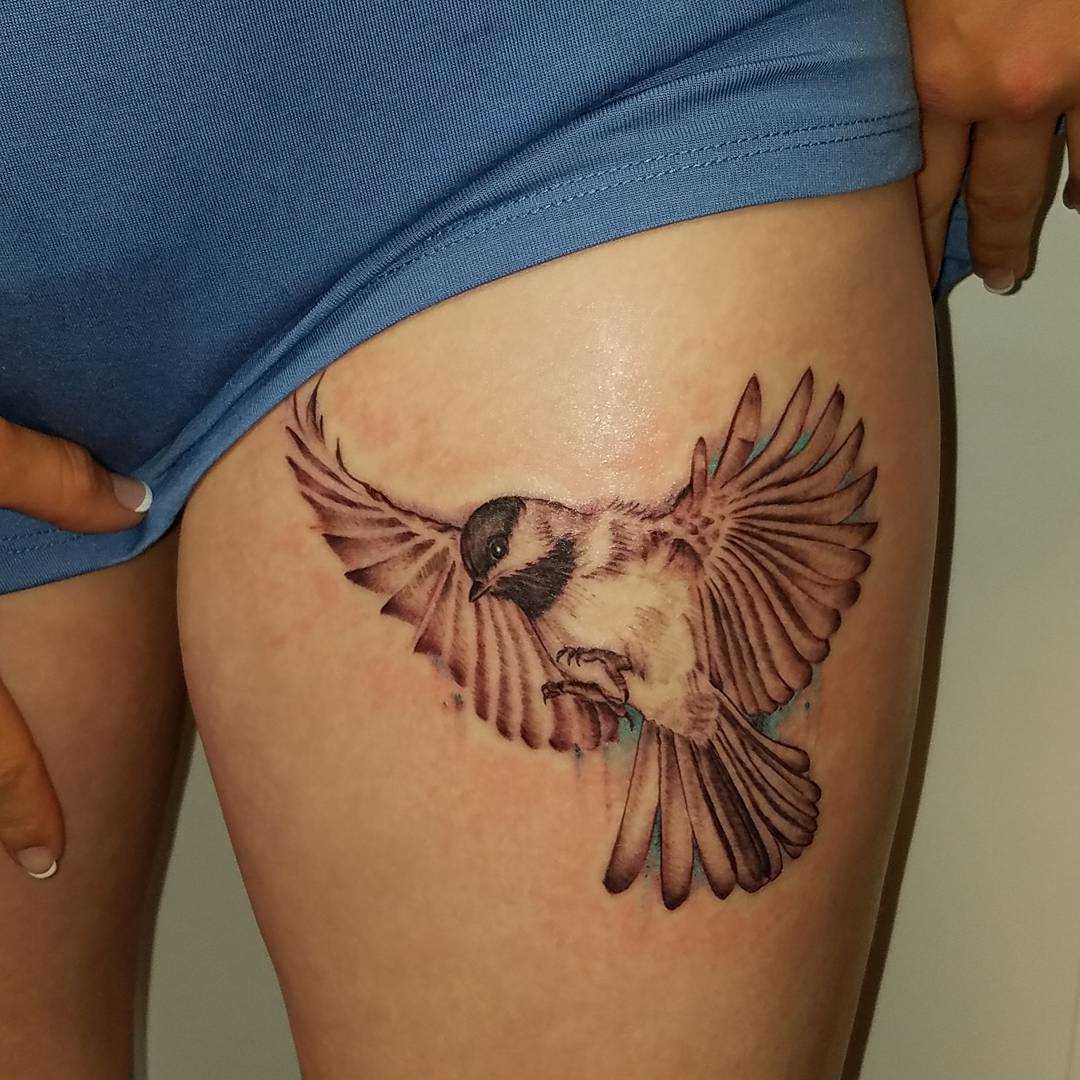 Tatuagem de um pardal no quadril da mulher
