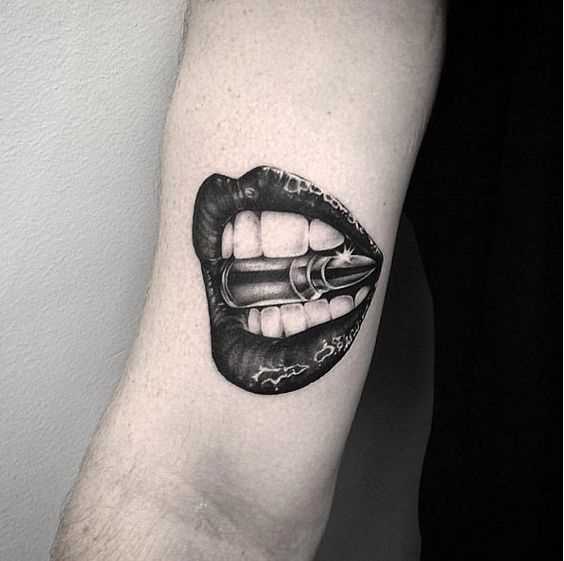 Tatuagem de uma bala na boca, no braço do cara