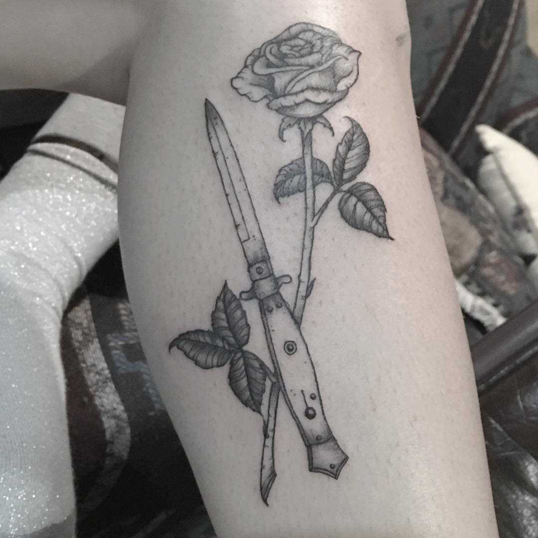 Tatuagem de uma faca com uma rosa na perna da menina