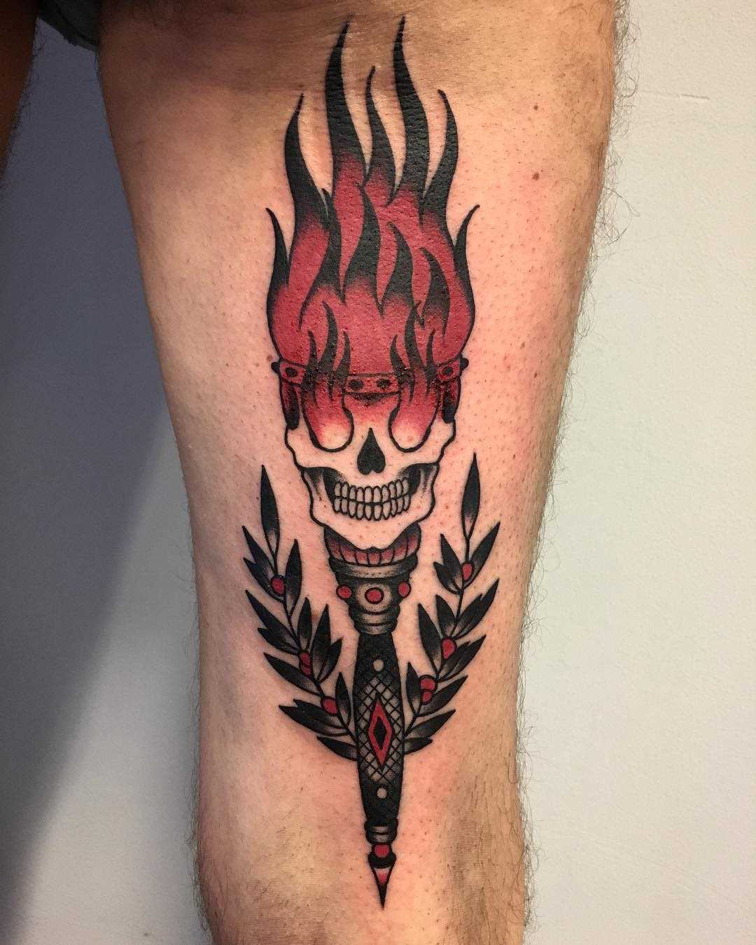 Tatuagem de uma tocha com um crânio na mão de um cara