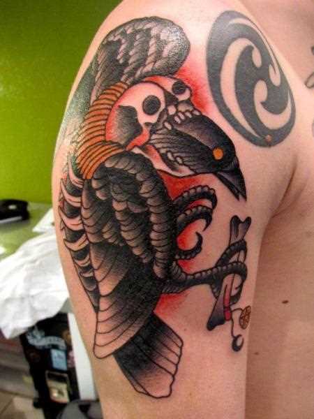 Tatuagem do corvo e do crânio no ombro do cara no estilo oldschool