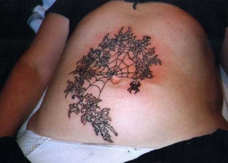 Tatuagem na barriga da menina - a web em um galho de árvore e a aranha