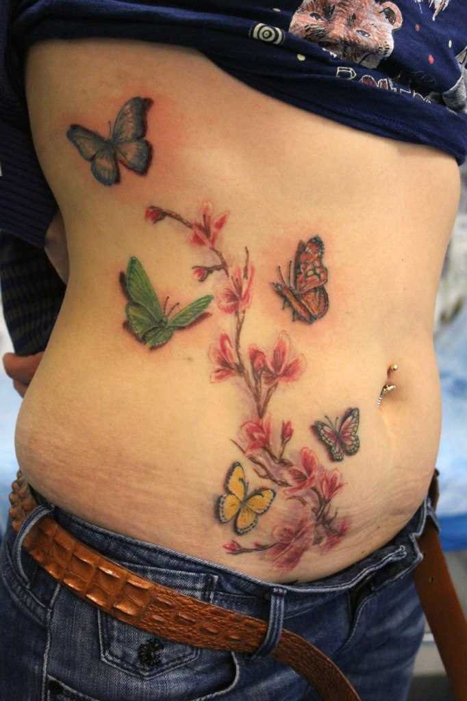 Tatuagem na barriga da menina - borboleta e sakura