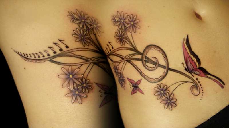 Tatuagem na barriga da menina - clave de sol, flores e uma borboleta