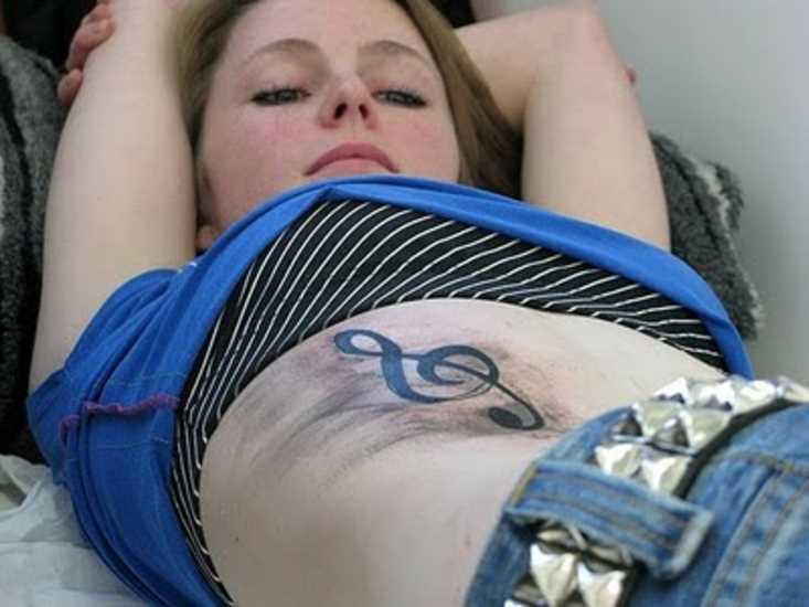 Tatuagem na barriga da menina - clave de sol